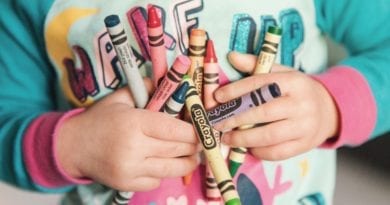 Child holding crayons while doing large group activities for toddlers