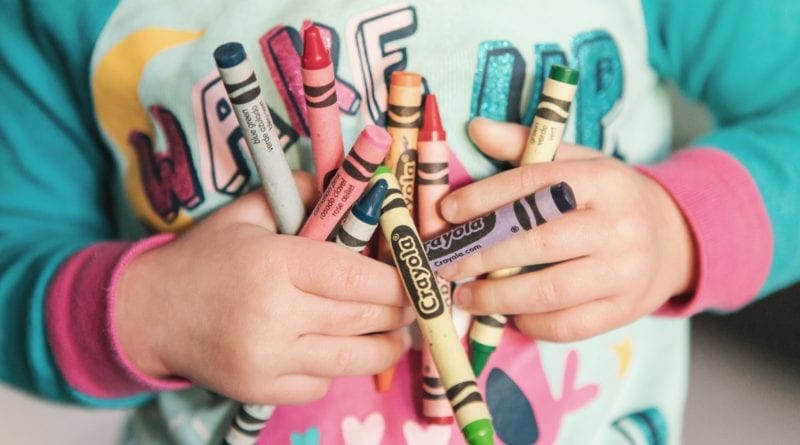 Child holding crayons while doing large group activities for toddlers